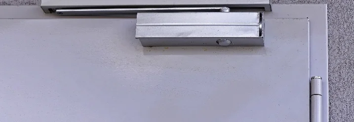 Ein Türschließer an einer grauen Tür.